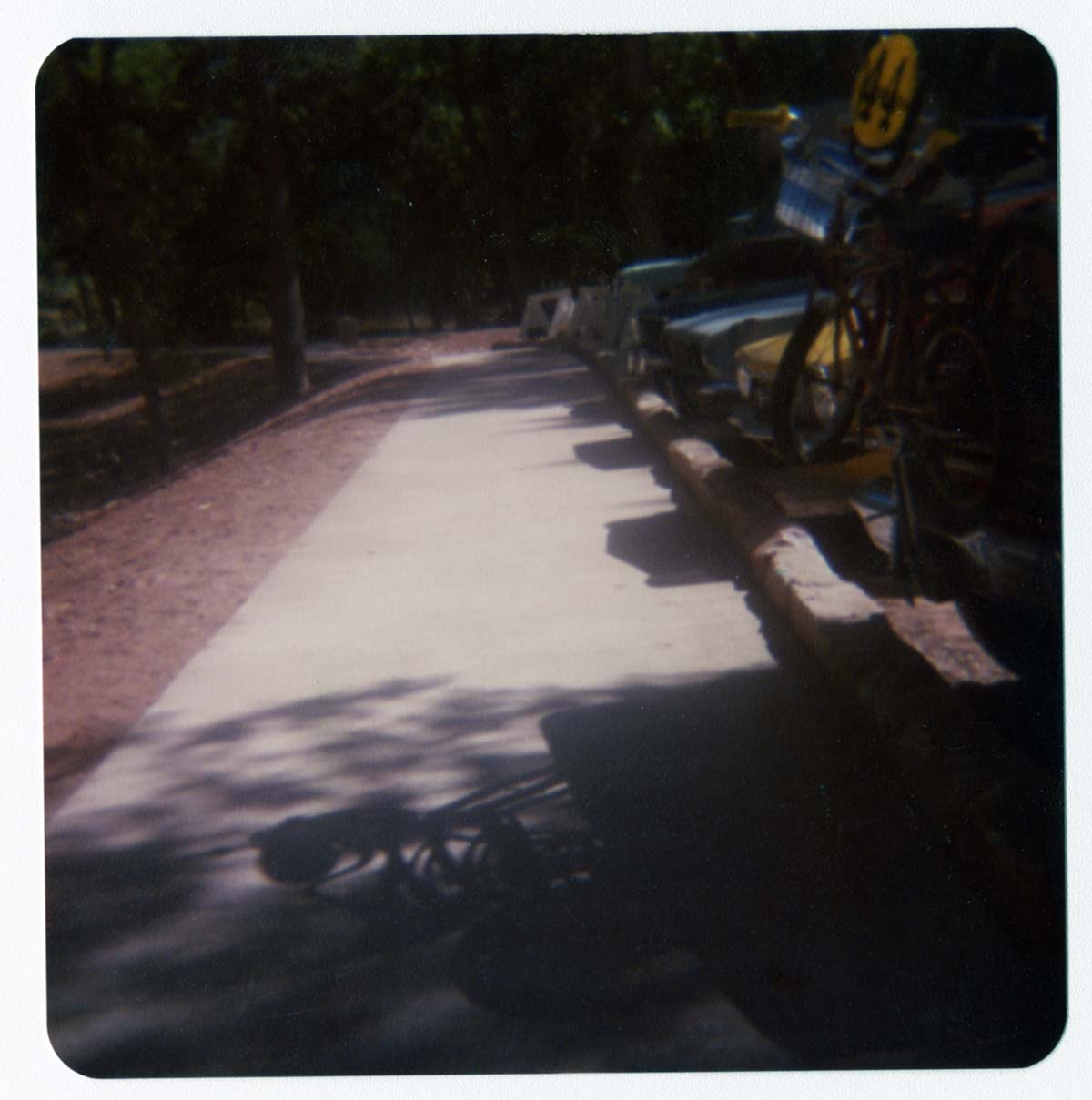 Completed sidewalk and parking area by the new Grotto footbridge. Cars and trucks parked along curb.