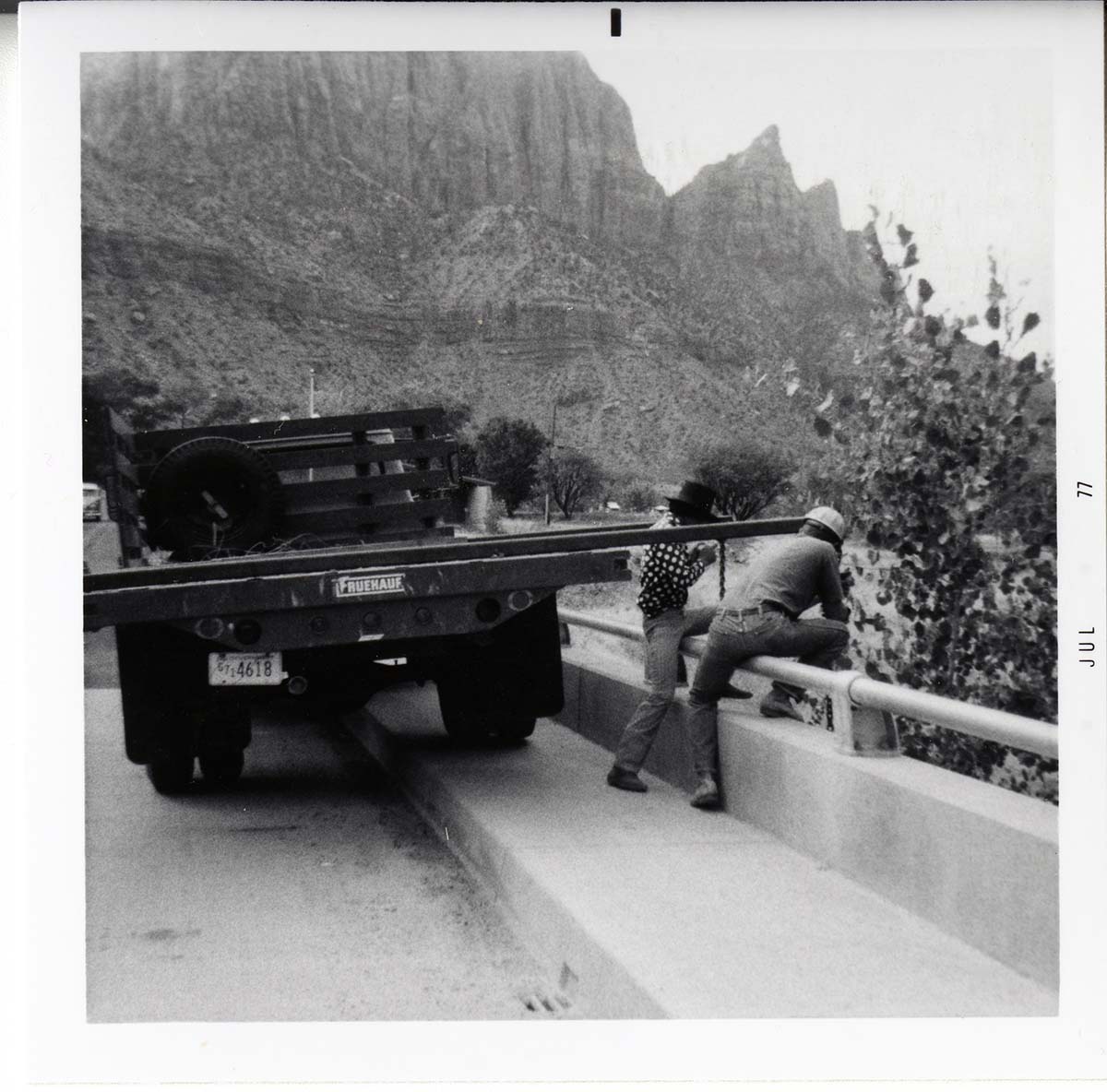 Workers place pipe on side of bridge during the Watchman housing utility project.