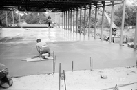 Workers leveling cement in corner during construction of headquarters addition.