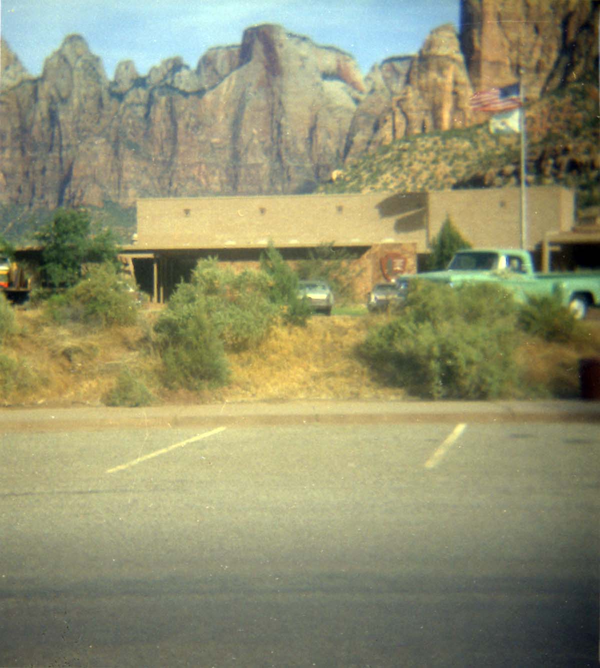 Vehicles parked in parking lot in front of the old Mission 66 Visitor Center and Museum.