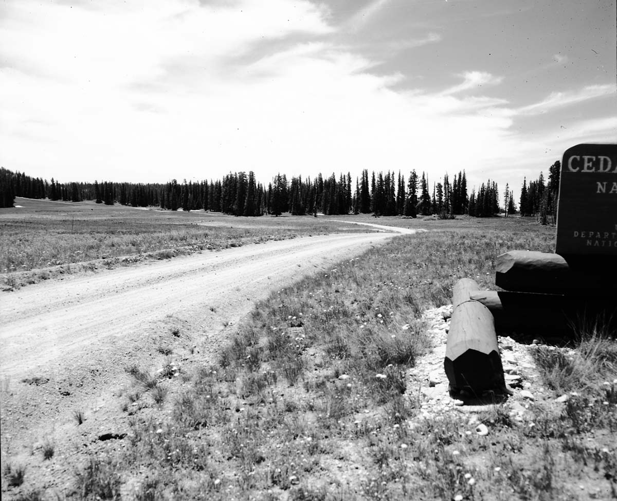 The rim road at the north entrance before 1960 construction project. Cedar Breaks National Monument entrance sign at right. Taken as a record of the project.