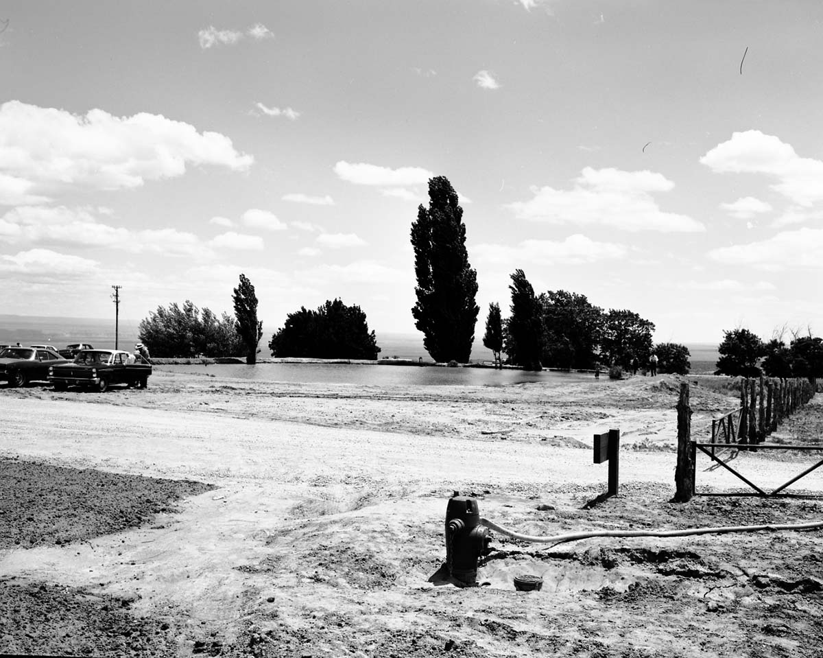 The visitors and cars around the cattle pond on Kaibab Paiute tribal lands, south of new Tribal and National Park Service Visitor Center at Pipe Spring National Monument. Fire hydrant and gate in foreground.
