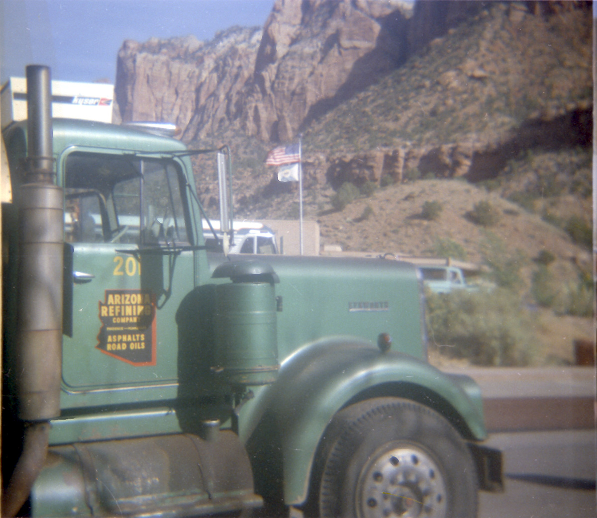 Front of 'Arizona Refining Company' truck with flag in background during sealcoating of parking area in Zion.