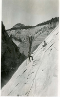 Two workers cutting the stone face for the West Rim Trail construction-1924.