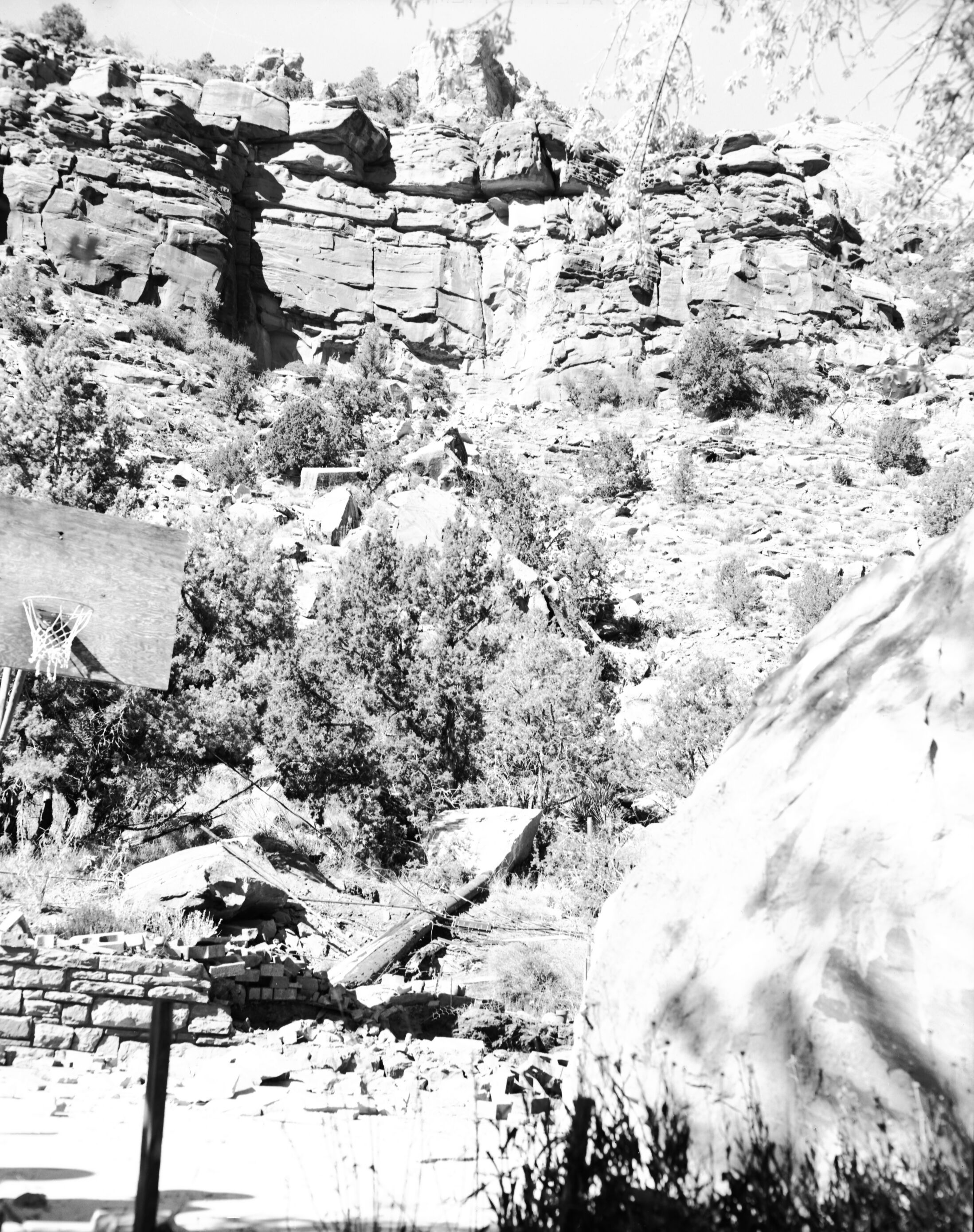 Rock fall behind Chief Ranger Fred Brueck's residence. Image shows men working near downed power pole. [Landslides, erosion]