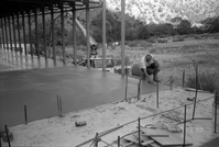 Workers leveling cement in corner during construction of headquarters addition.