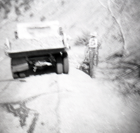 Man shoveling dirt from back of truck to use during road work.