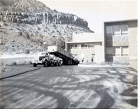 Paving of employee parking area, Mission 66 Visitor Center and Museum. Truck pouring hot mix at loading dock area.