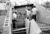 Men shoveling gravel/cement during the construction of headquarters addition.
