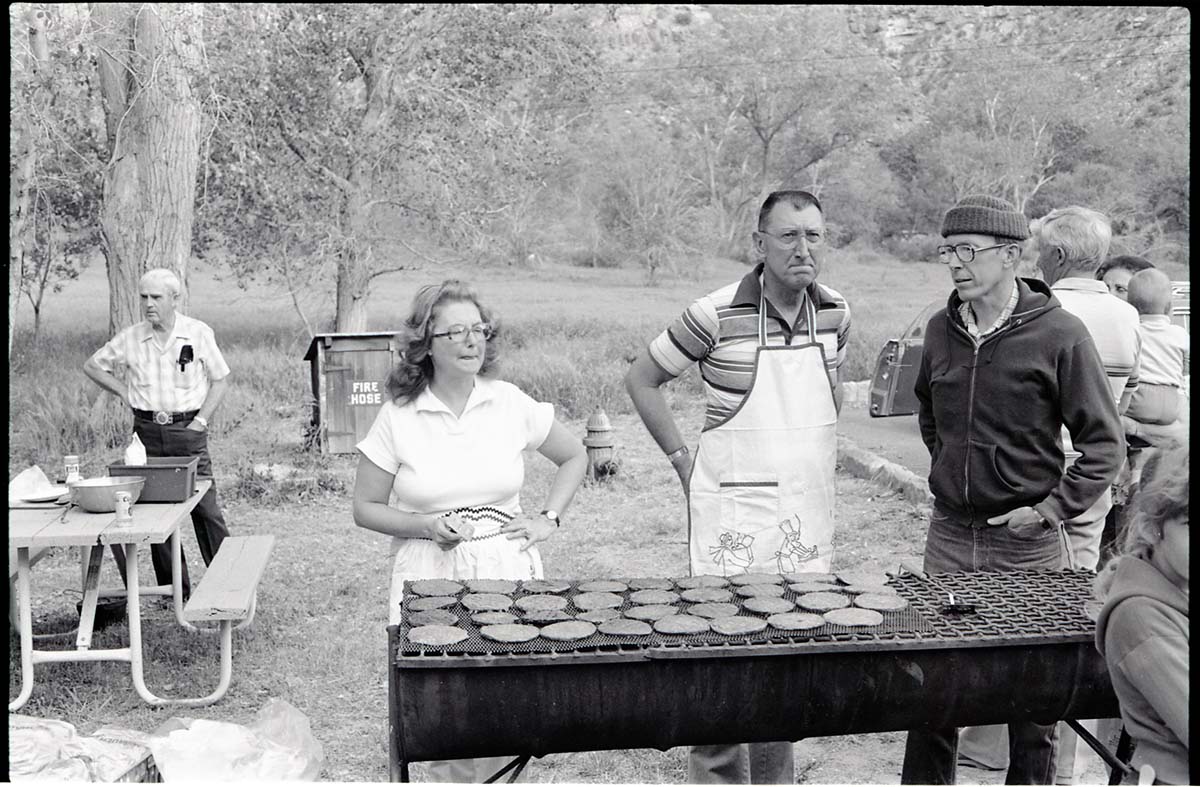 BW Photos of the Crocker/ Nicholson retirement barbeque. Superintendent Harold Grafe in apron at grill with man and woman.