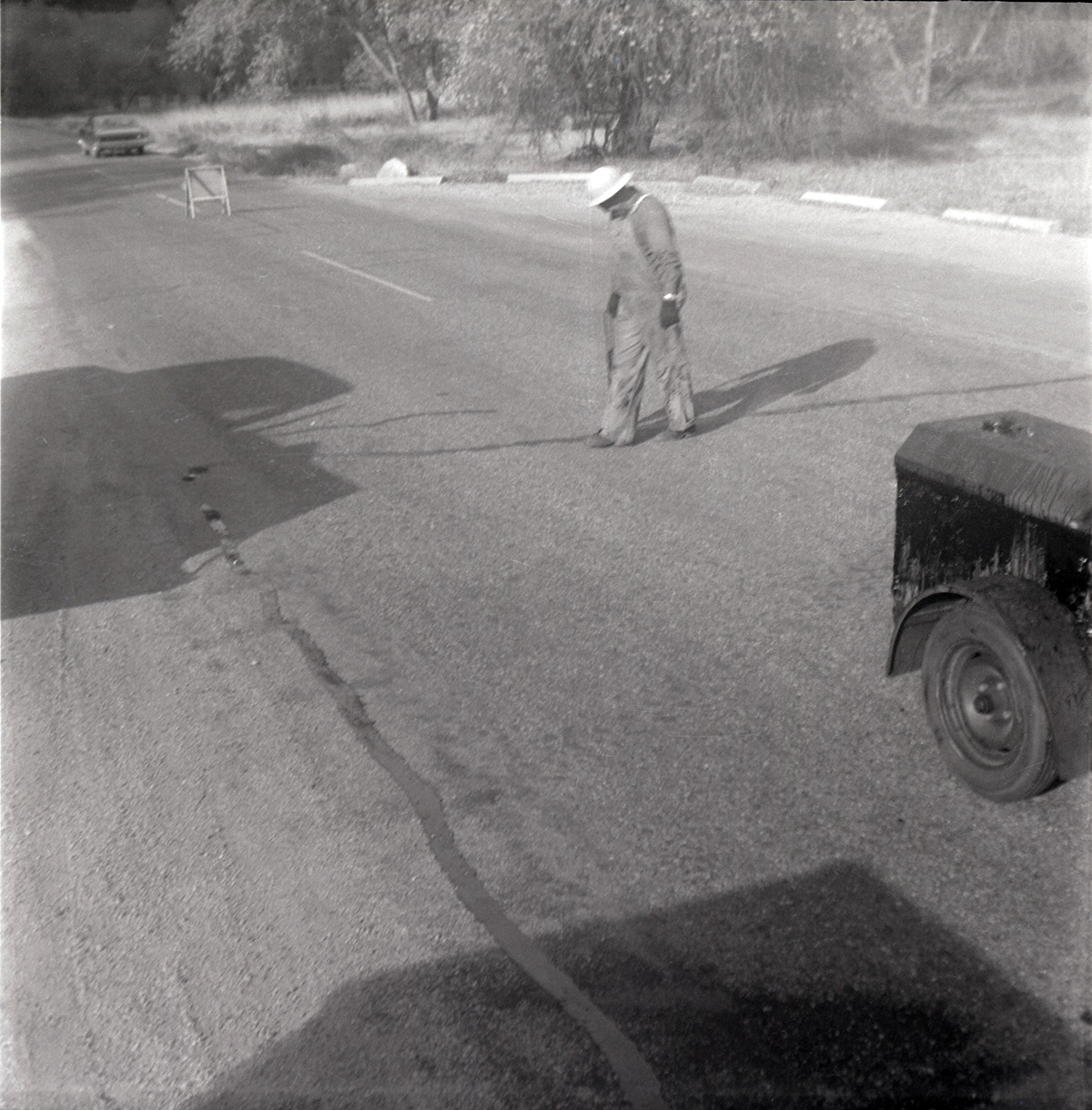 Man filling crack in road along the scenic canyon drive near the Grotto.