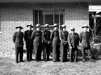 Rangers in uniform standing with Rudy Lueck (third from left) and Carl E. Jepson (second from right) outside Mission 66 Visitor Center and Museum and headquarters. Superintendent Warren F. Hamilton at far right.