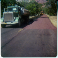 Construction vehicles sealcoating the road.
