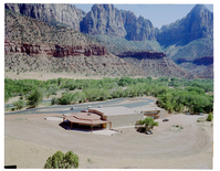 The old visitor's center and headquarters building and surrounding dirt lot, view south.