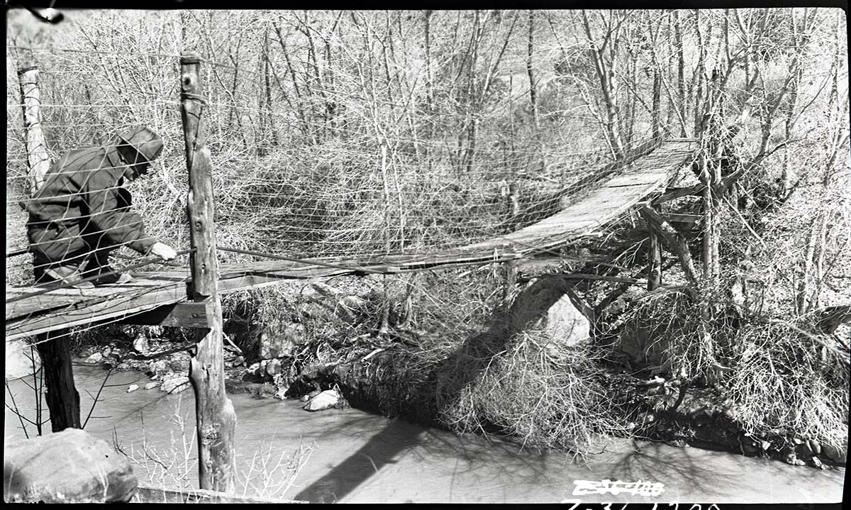 Park ranger checking cable on Birch Creek trail suspension bridge over Virgin River.