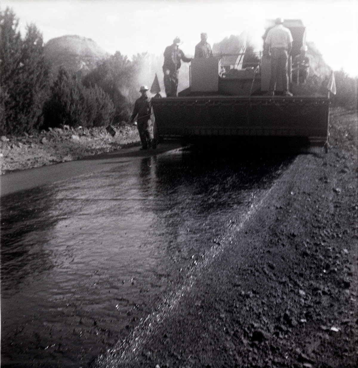 Men operating construction vehicles during chipsealing of Kolob Canyon Road.