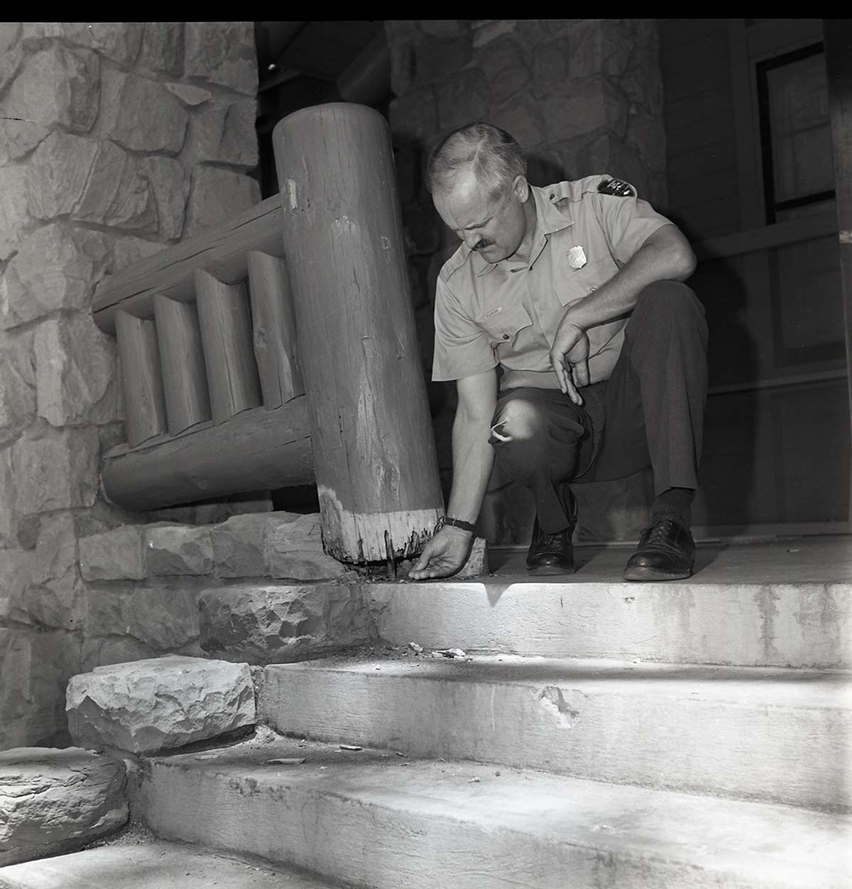 Damage to railing at men's dorm at Zion Lodge. Superintendent Robert C. Heyder pointing to rotten wood.
