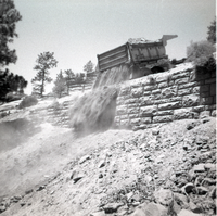 Dump truck dumping dirt over retaining wall during repairs of all along East Rim road.