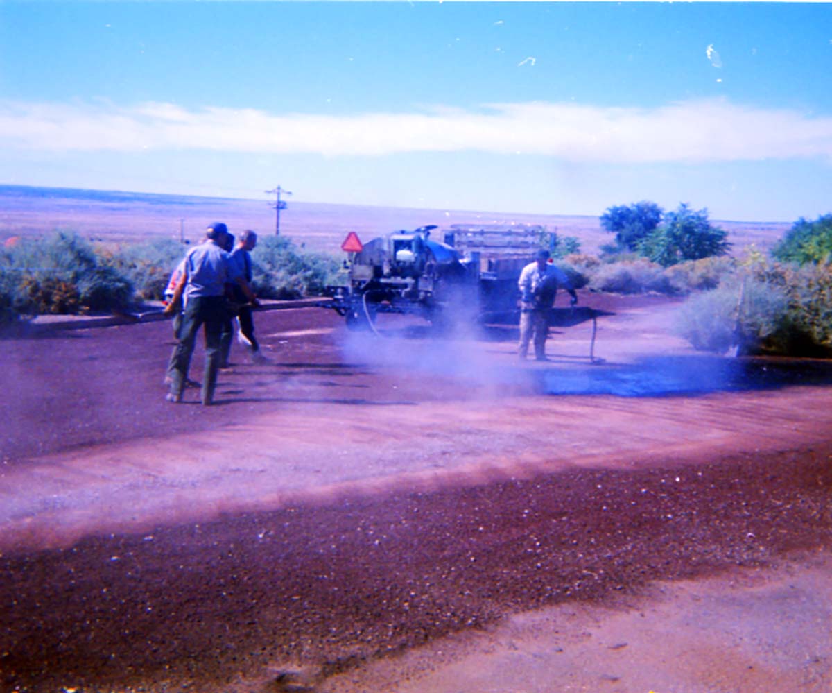 Color Photos of workers chip sealing the parking lot at Pipe Spring.