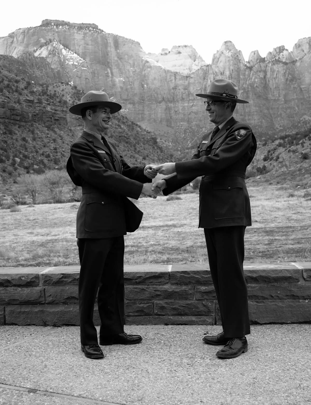 Superintendent Warren F. Hamilton presenting Assistant Chief Ranger Fred Brueck with Service Award pin for 30 years pf service, West Temple and Towers of the Virgin in the background.