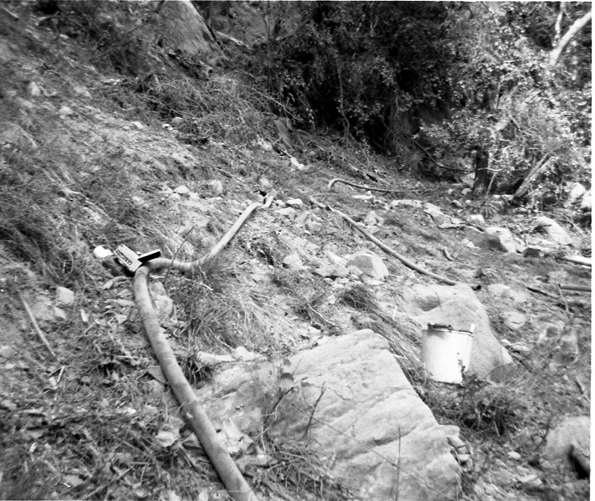Pipe damaged by rubble from rock slide. Bucket in foreground. Birch Creek.