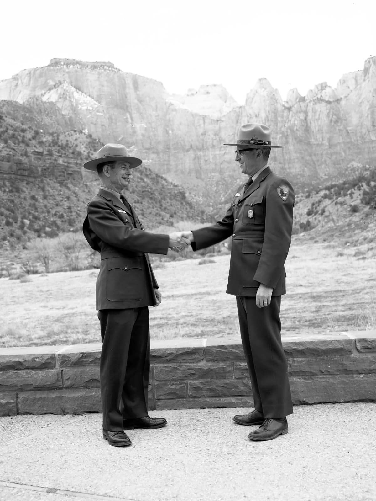 Superintendent Warren F. Hamilton presenting Assistant Chief Ranger Fred Brueck with Service Award pin for 30 years pf service, West Temple and Towers of the Virgin in the background.