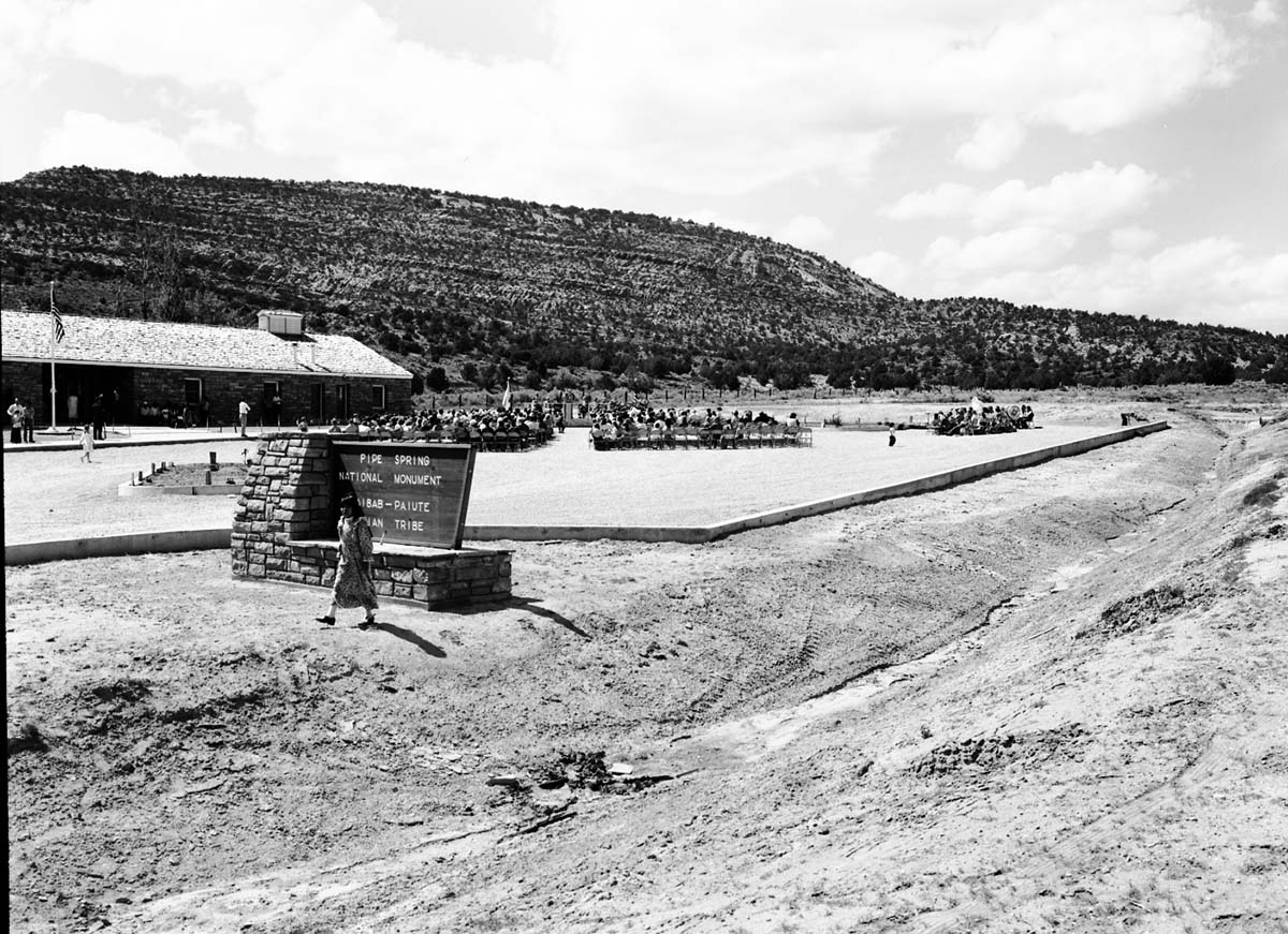 Crowds gathered for the dedication ceremony of new Tribal and National Park Service Visitor Center and celebration of the 50th anniversary of Pipe Spring National Monument. Looking at celebration from roadway.