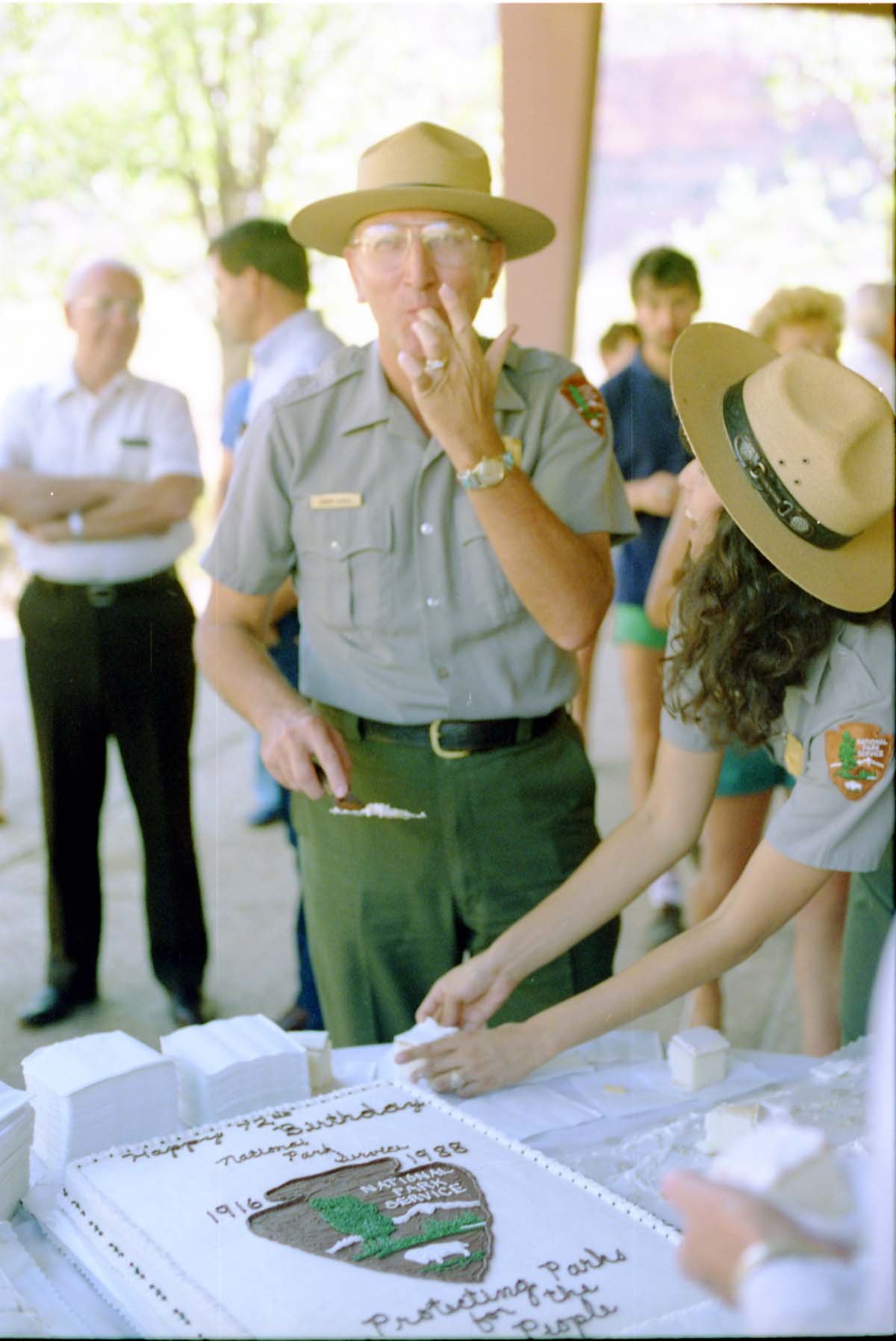 Color Photos of the parks 72nd anniversary celebrations- cake cutting, barbecue, speakers. Superintendent Harold Grafe serving cake with Blanca Stransky.