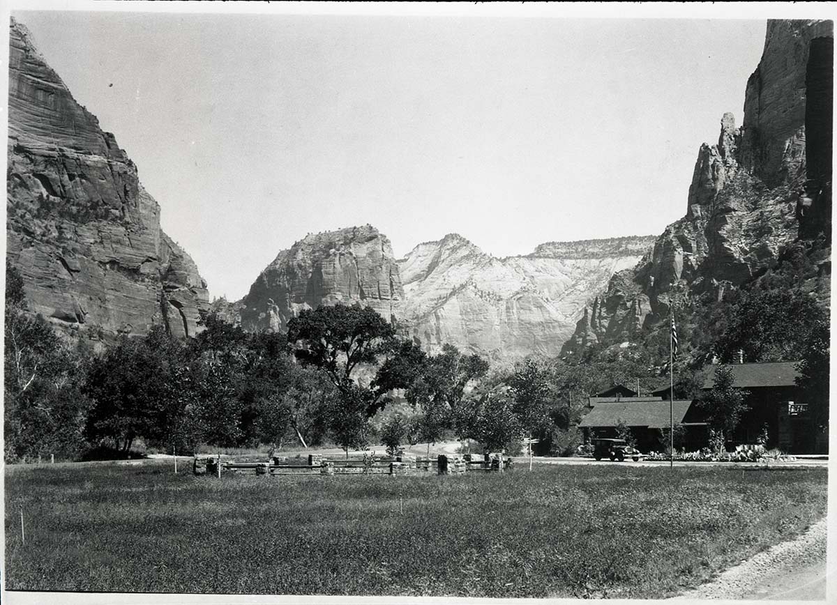 Zion Lodge circa 1930, view of the lodge looking north with Angels Landing in the distance and vintage vehicle parked in the drive.