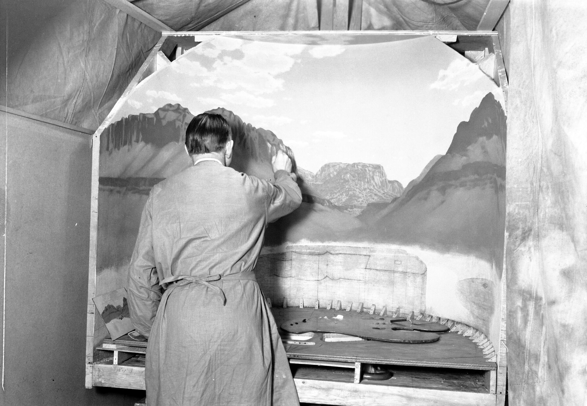 Worker painting the background for the Zion Museum's Indian Pueblo diorama exhibit. Western Museum Laboratory (WML) on Fulton Street, Berkeley, California.