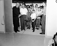 Associate Director Eivind T. Scoyen and Senator Frank E. Moss cutting the ribbon at entrance to Mission 66 Visitor Center and Museum, with children and visitors watching.
