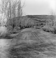 Wayside panel exhibit and plow next to the road and footbridge leading to residential area.