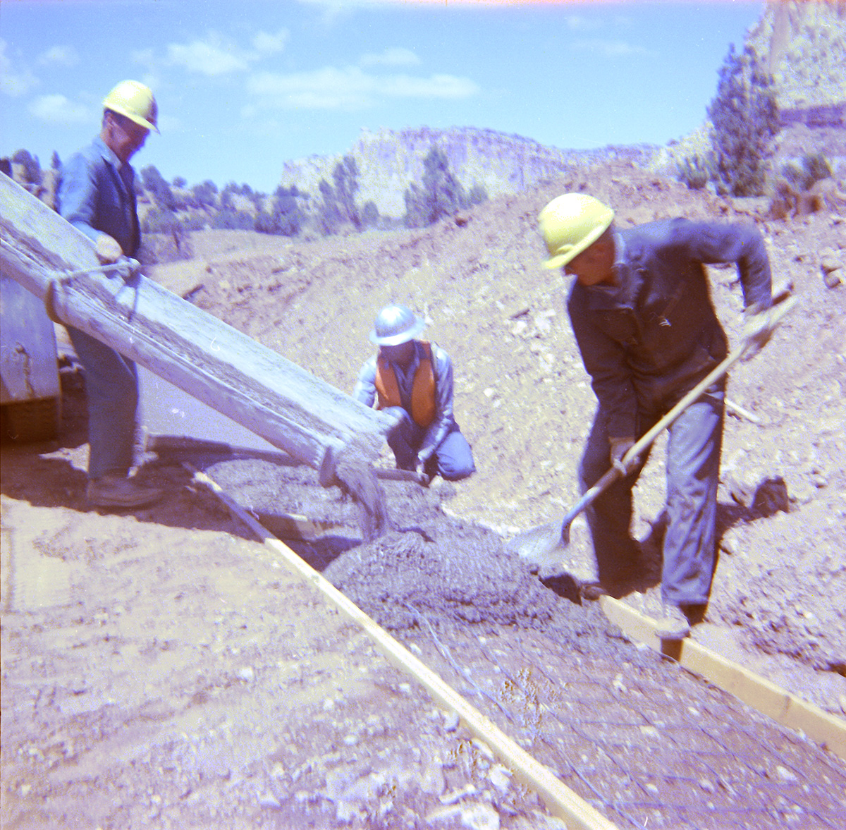 Men laying and leveling cement during road construction and repair.