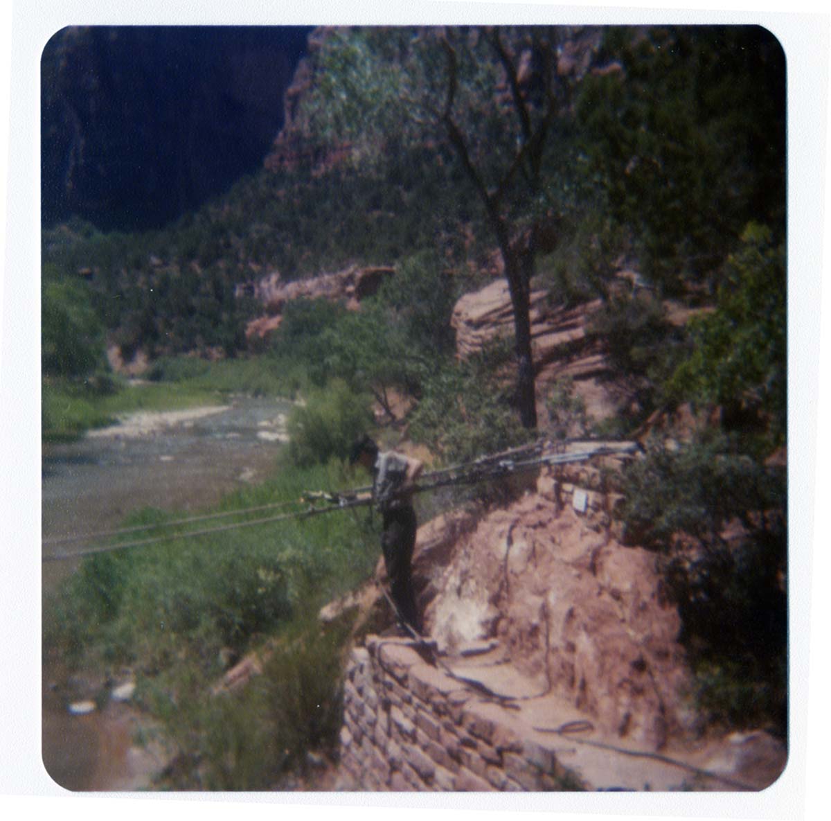 Man tightening cables for pulley system to move new Grotto footbridge across the Virgin River.