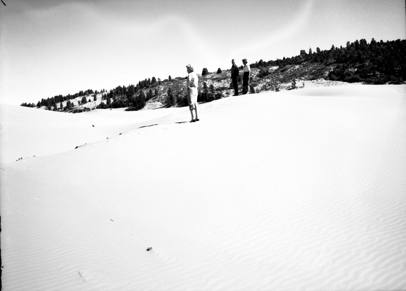 Man and two women walking on the sand at Coral Pink Sand Dunes near Kanab, Utah.