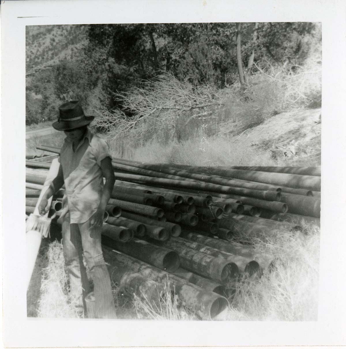 Navajo worker standing next to a pile of pipes during the Watchman housing utility project.