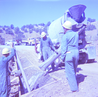Men filling road side sections with gravel and dirt during road repair.