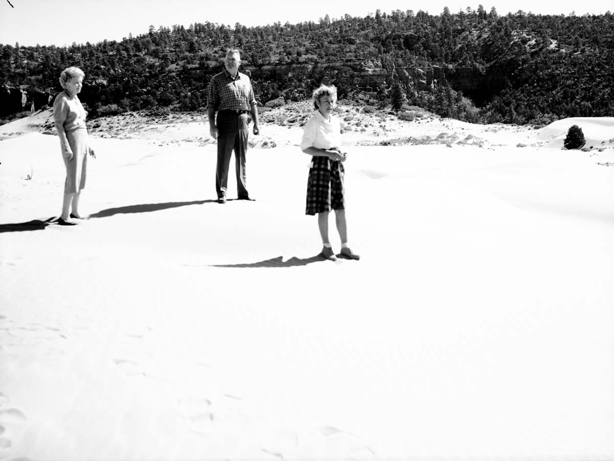 Man and two women standing on the sand at Coral Pink Sand Dunes near Kanab, Utah.