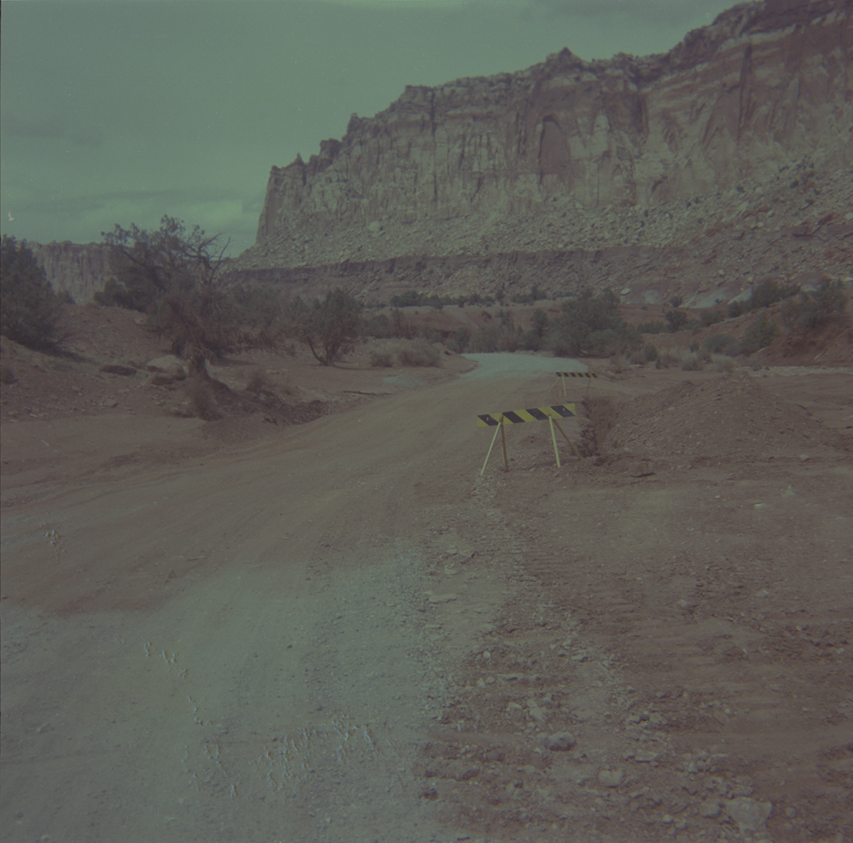 Dirt road with caution stand and Zion landscape in background.