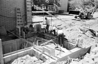 Men preparing foundation for cement during construction of headquarters addition.