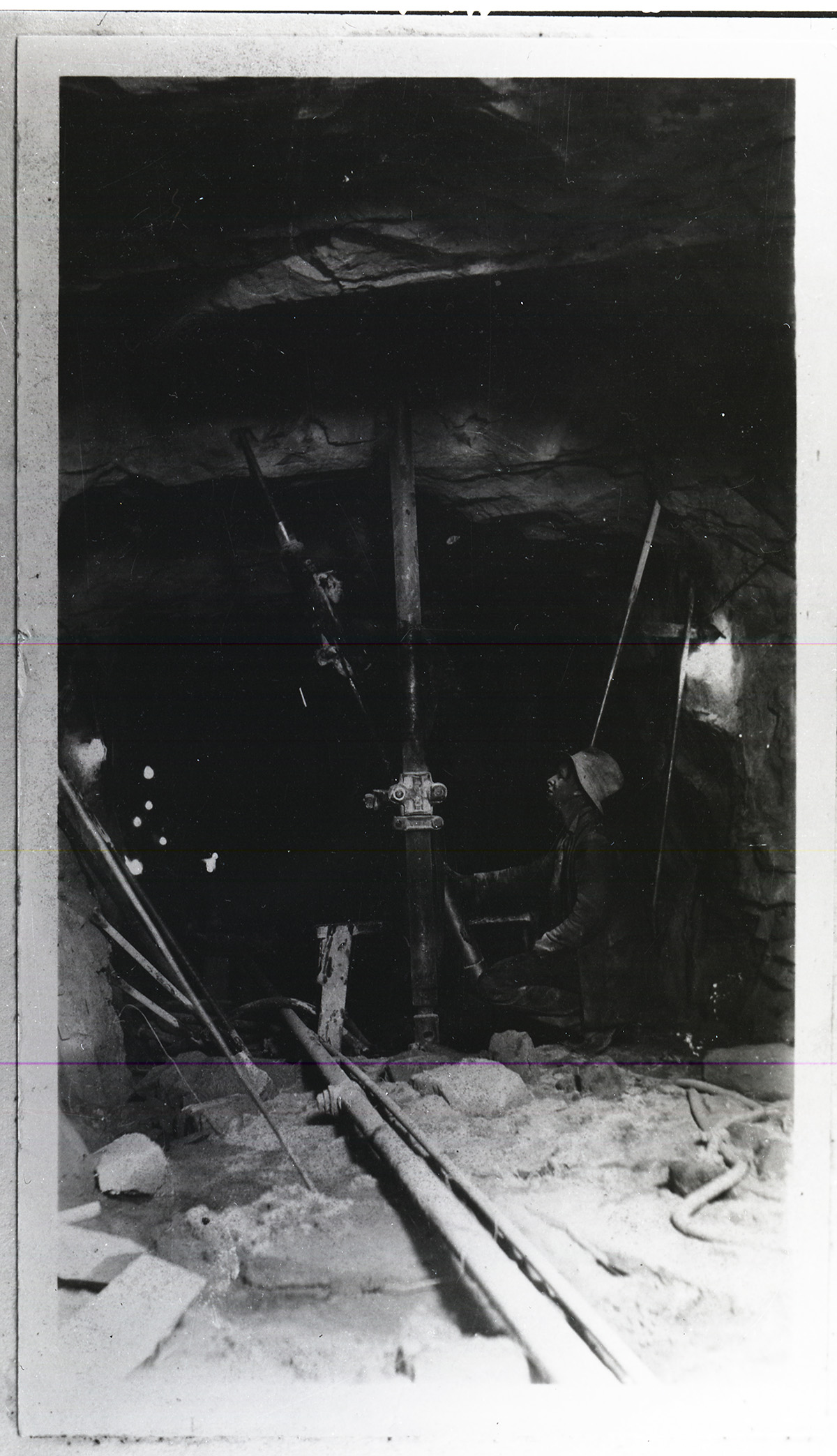 Worker using jack and drill in large tunnel.