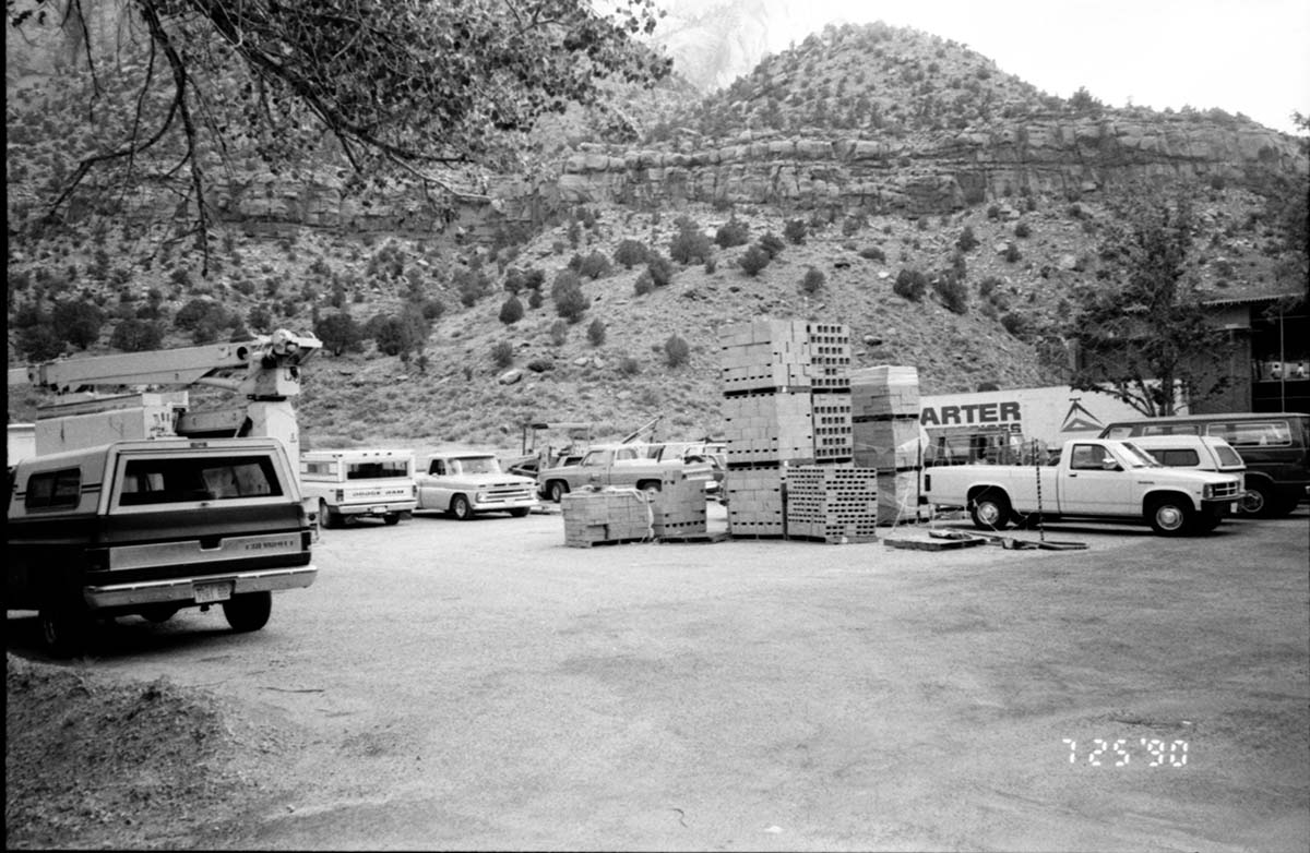 Parking lot with construction vehicles and building materials during the construction of headquarters addition.
