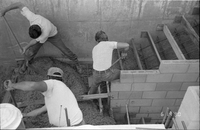 Men shoveling gravel/cement during the construction of headquarters addition.