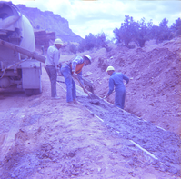 Men leveling cement during road repair.